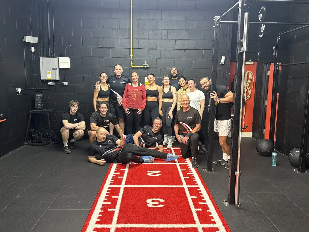A mixed group of Challenge Life members smiling together in the gym